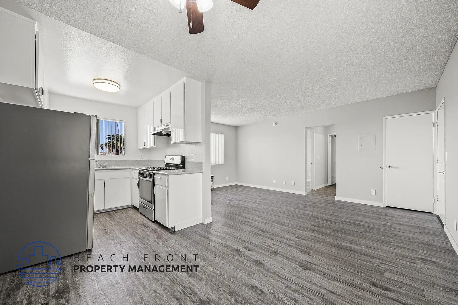 A spacious kitchen with white cabinets and a wooden floor.